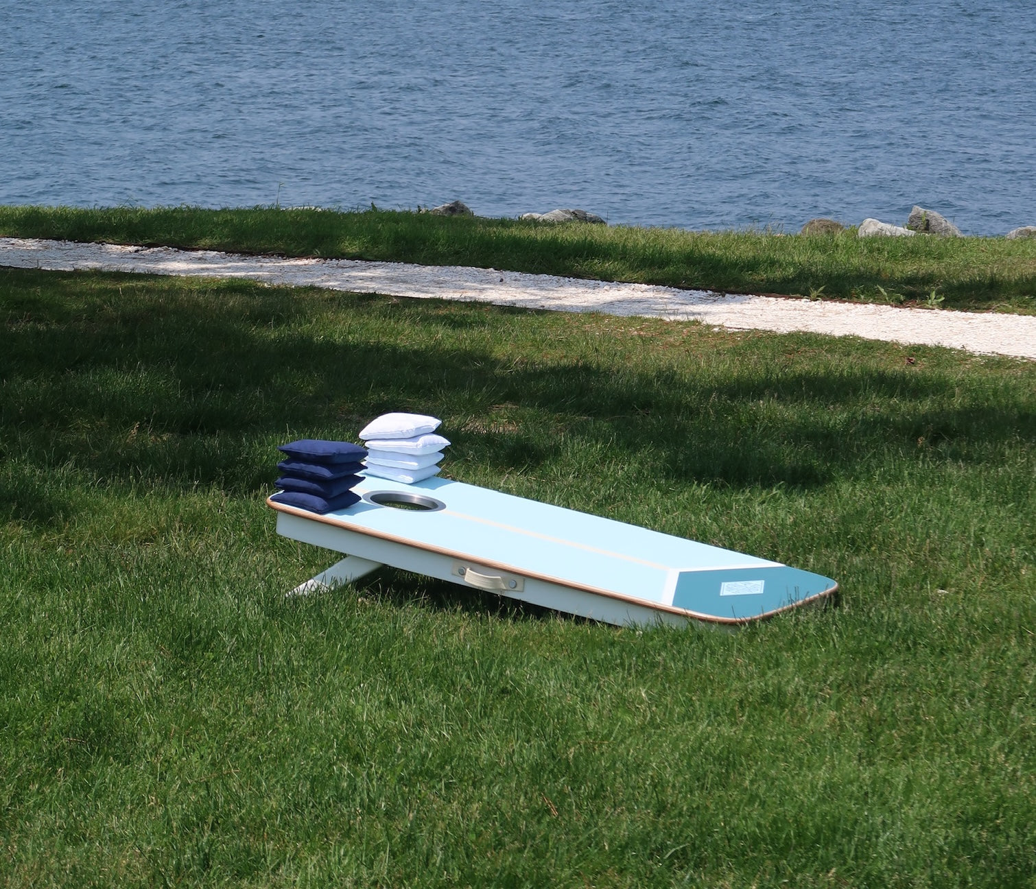 Close up of American Saturdays luxury cornhole board on a lawn by the atlantic ocean